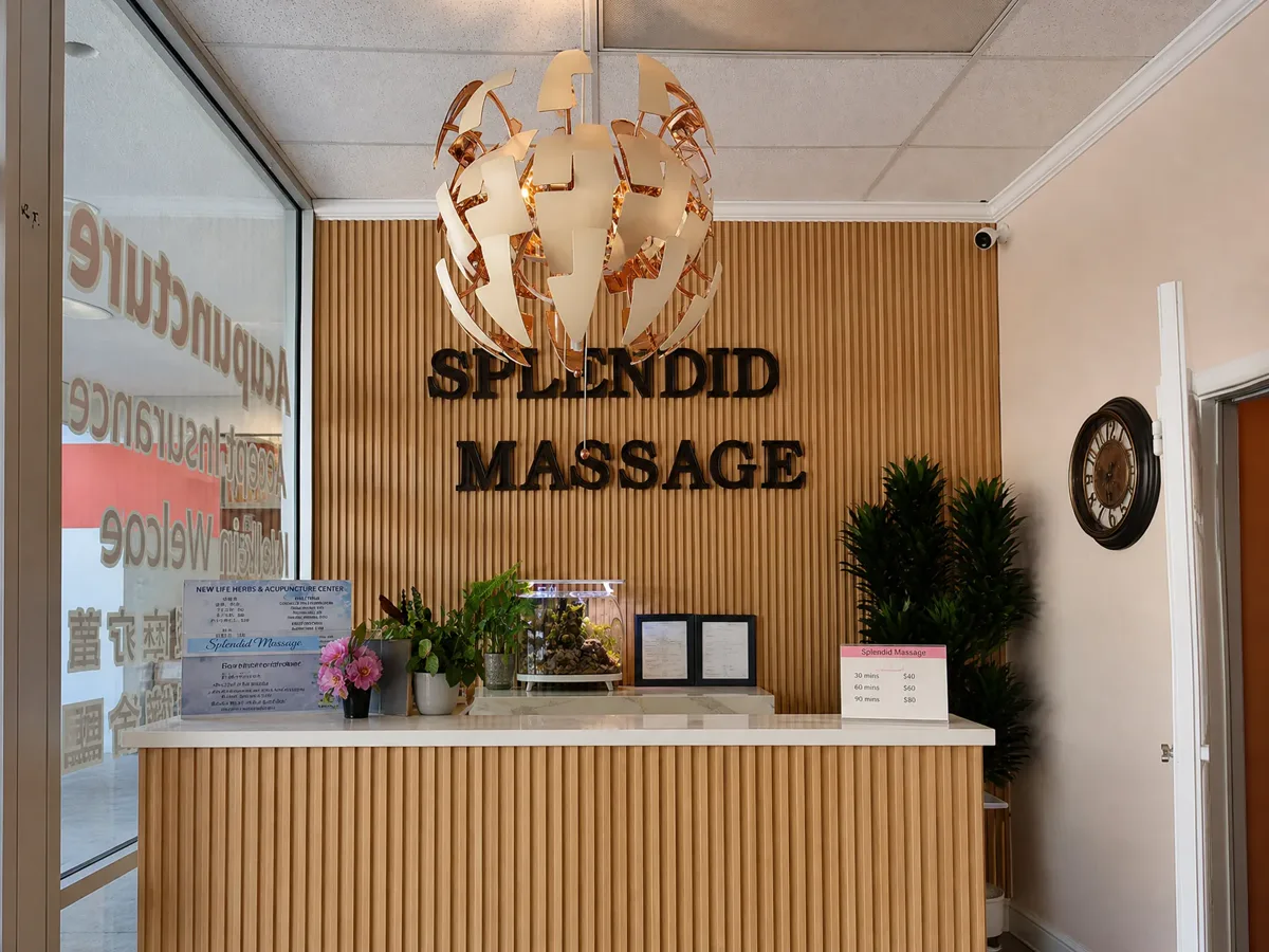 Front desk with the Splendid Massage sign on a wood-slat wall